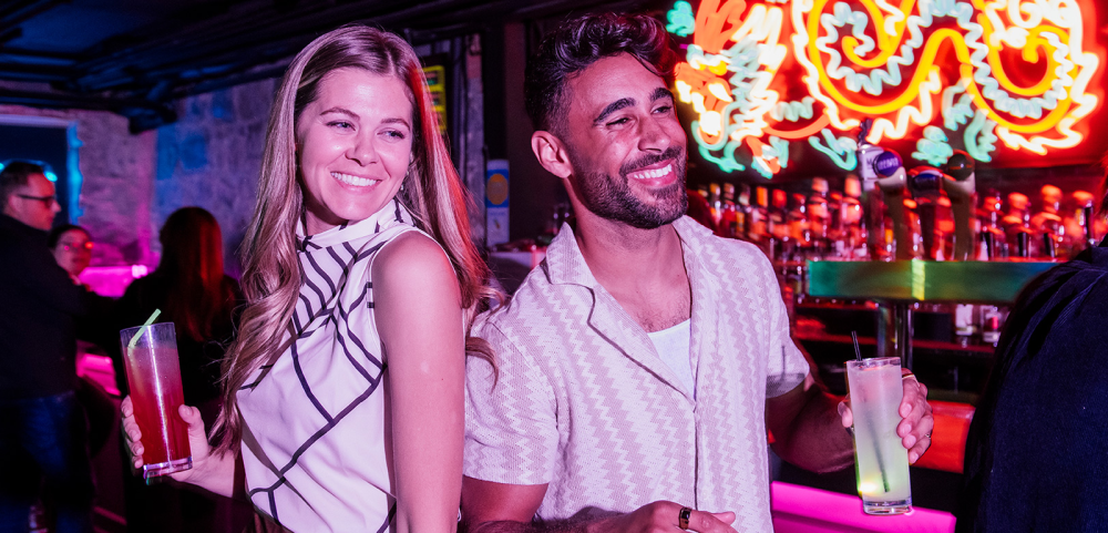 Couple having drinks at Lo-Fi with neon sign behind