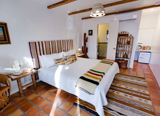 A cozy bedroom with a white bed, wood-beam ceiling, and Southwestern decor.