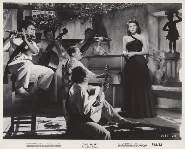 Scene from film The Bribe featuring Ava Gardner in one-shouldered black dress standing next to piano