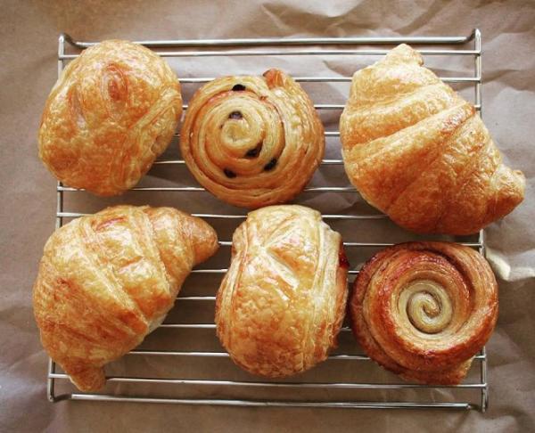 Six assorted croissants and rolls on a cooling rack from Mi-Sant Banh Mi