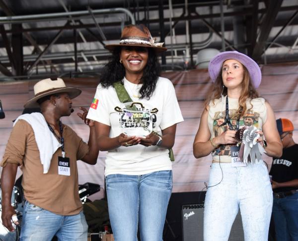 NOLA Zydeco Fest executive director Gabrielle Deculus smiles while holding an award onstage alongside festival volunteers at the 2025 festival in Slidel