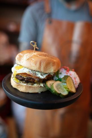 a black plate with a hamburger and pickle slices