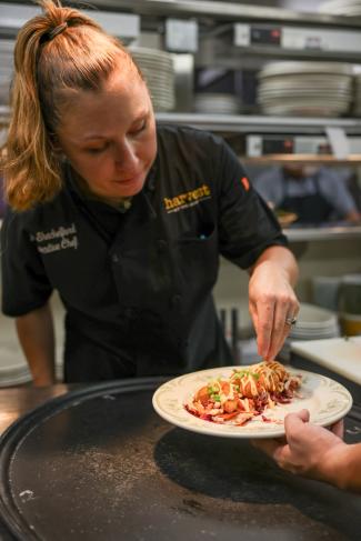 Female chef adds touches to plated food