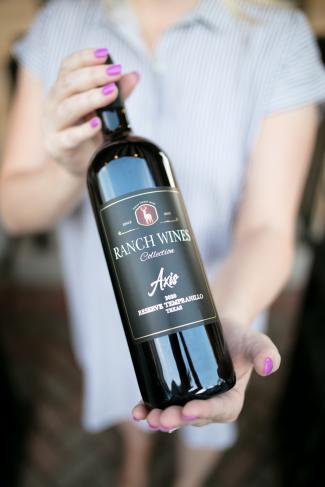 woman's hands holding a wine bottle for the camera