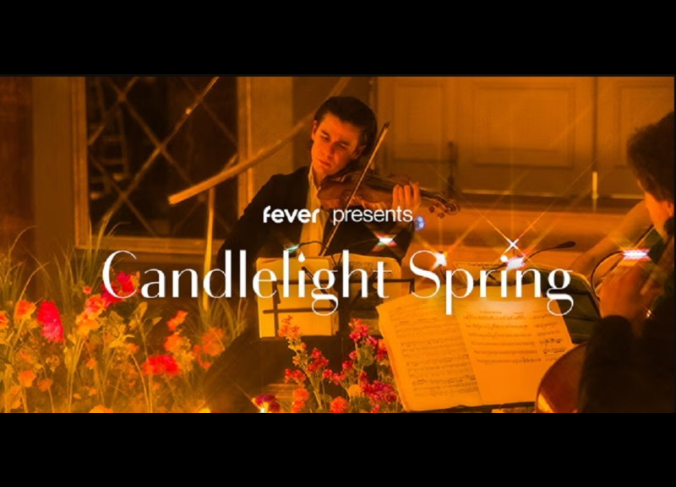 Image is of a violin player playing while surrounded by flowers and candlelight.