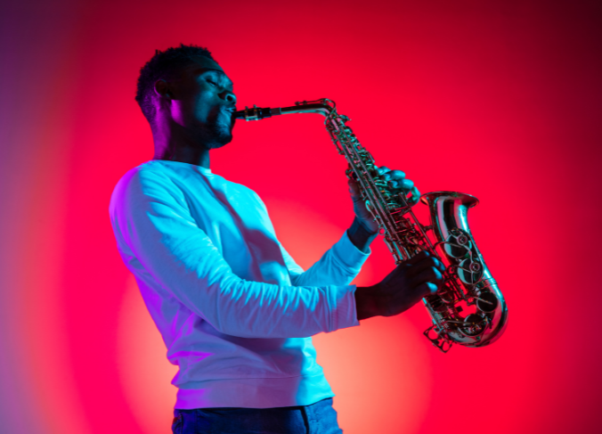 Image is of a man playing paying a saxophone.