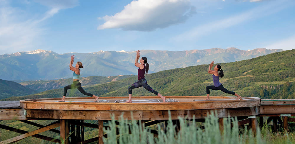 three people doing yoga with a mountain view