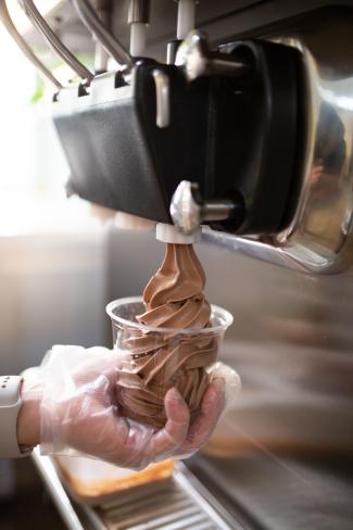 hands serving ice cream from soft serve machine