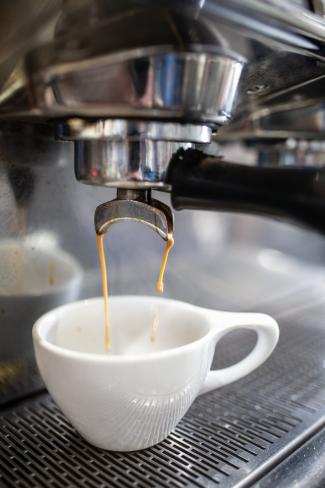 white coffee mug under a machine with coffee dripping into it