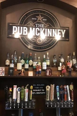 The Pub sign behind beer bottles and taps