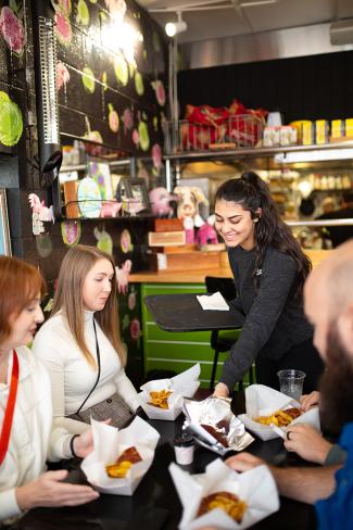young woman serves food to a table of people in a restaurant