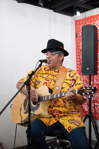 Guitarist wearing a bright yellow shirt and black hat
