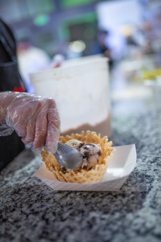 hand Scooping ice cream into a waffle cup