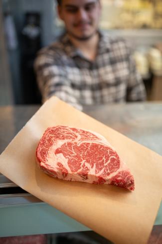 marbeled steak being handed toward camera