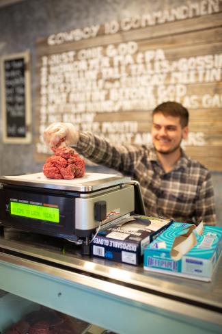 young man measuring ground beef on scale