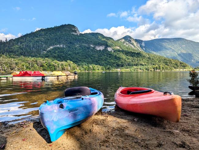 Boats on the Shore of a Scenic Lake with Mountains in the Background