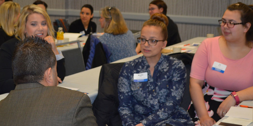 Event participants listen intently while seated at a table