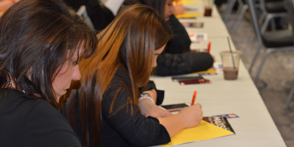 A woman jots down notes on a yellow sheet of paper during the March 2018 Industry Insider Training