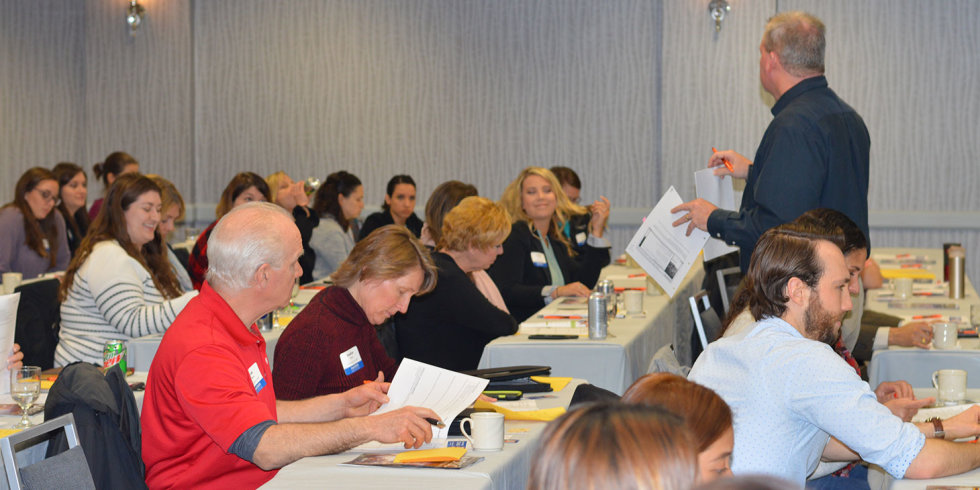 A man holds up a sheet of paper while presenting at the March 2018 Industry Insider Training
