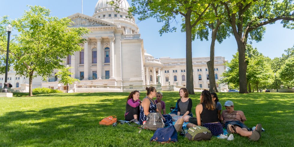 A group of people sit around a blanket and enjoy a picnic on the Capitol lawn
