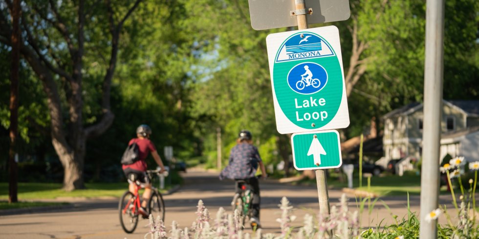 Bicyclists ride past a Lake Monona loop sign