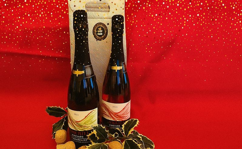 Two bottles of Larkhill wine with gift box and holly against a red background