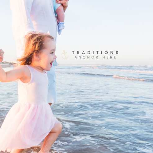 A little girl runs into the ocean while holding her parents' hands. Next to her head is a small logo reading "Traditions Anchor Here"