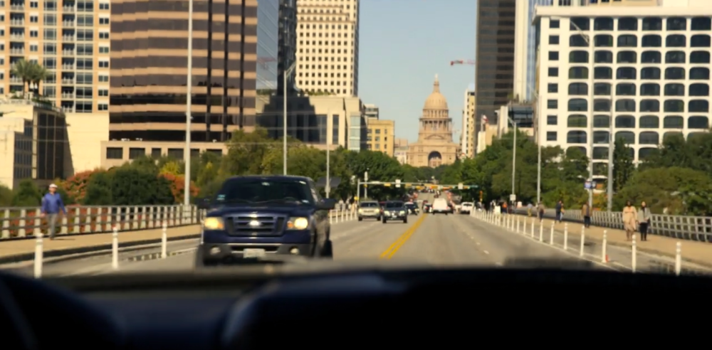 Walker screengrab. The camera is looking north on the Congress Avenue Bridge towards the Texas Capitol building