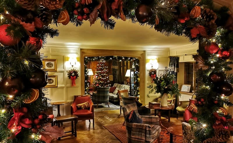 A garland covered in lights and baubles frames a lounge at Hatherley Manor