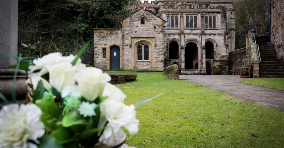 A view of flowers and the building to St Winefride's Well in the background