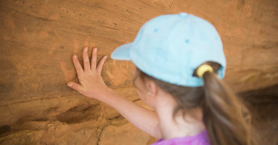 Girl with hand on handprint on a rock