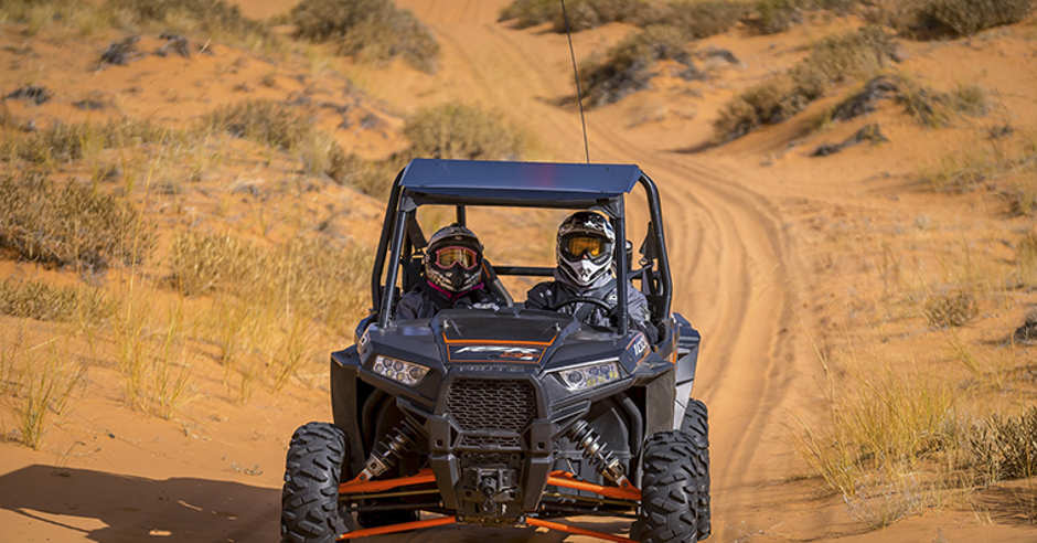 Two riders riding a Side-by-Side (SXS) OHV in the sand near Kanab, Utah