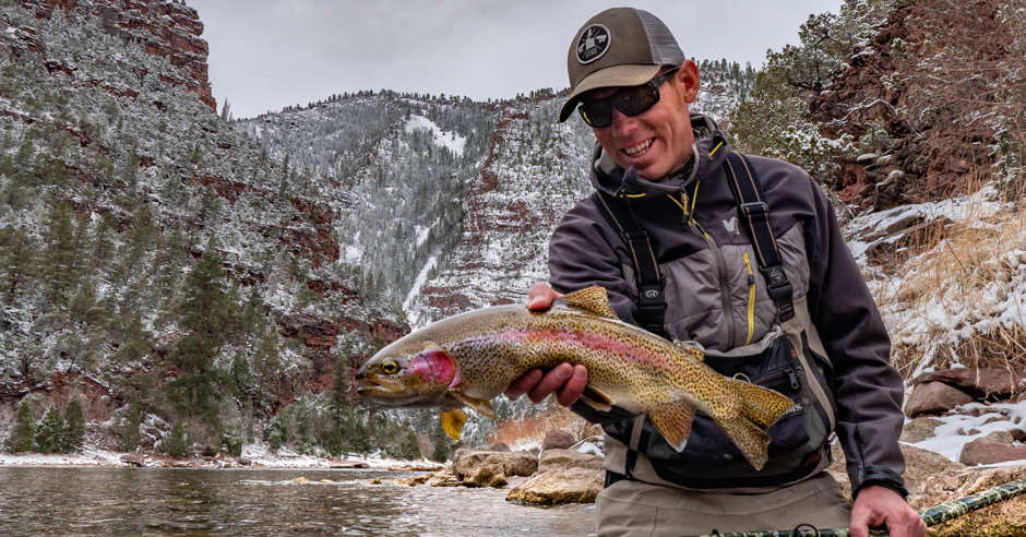 Man holding a rainbow trout fish while fishing in the winter