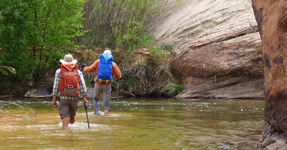 Two backpackers crossing a stream