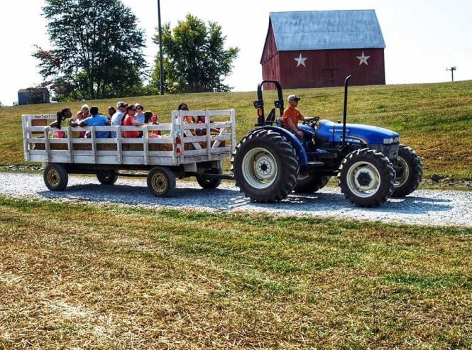 Tractor pulls people in a wagon an a farm