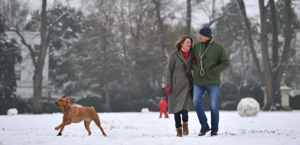 Visitors walking their dog through a snow filled park in Cheltenham