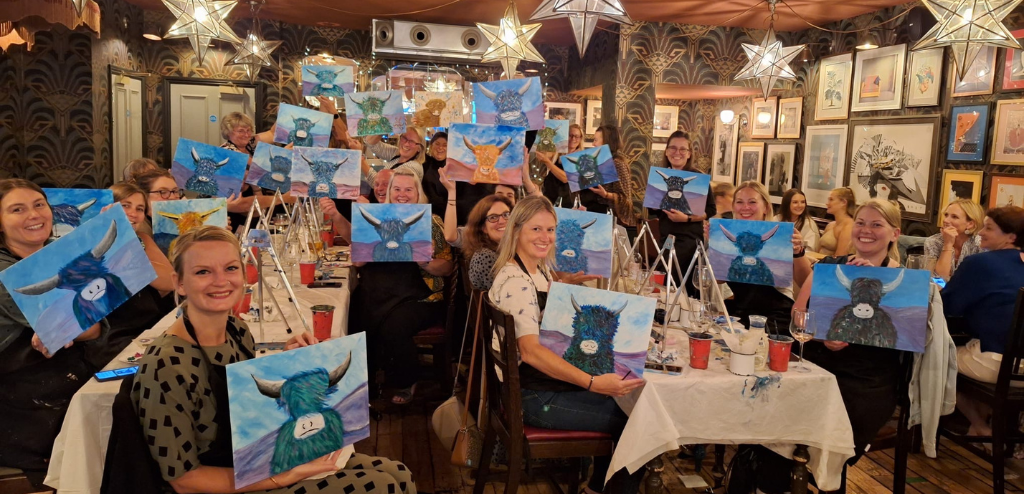 People holding their artwork at The Paint Club workshops.
