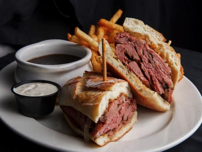 Plate with French dip with thick cuts of beef served with side of French fries