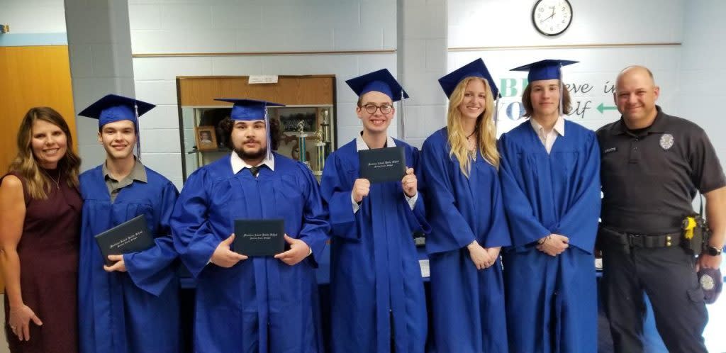 Graduates in the Mackinac Island Public School Class of 2022 hold their diplomas while wearing cap and gown.