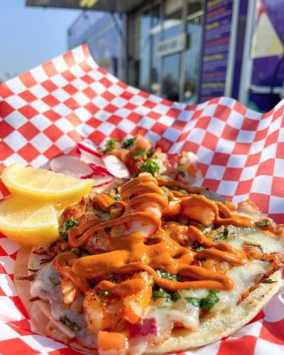 Photo of shrimp taco with food truck in the background