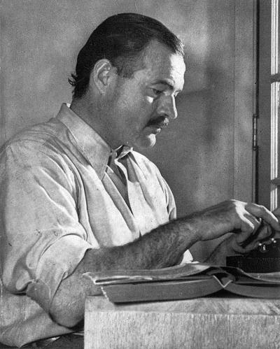 Ernest Hemingway sitting at a desk