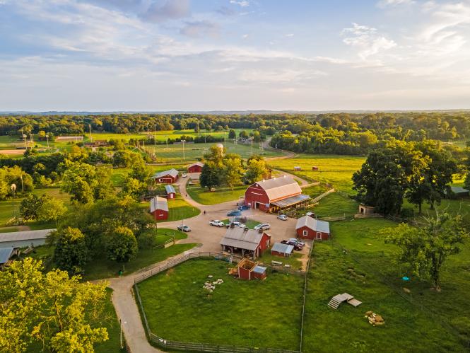 An aerial view of a farm with red barns in a field