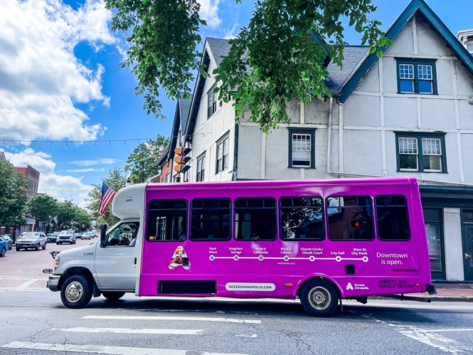A purple shuttle bus turns a corner in downtown Annapolis