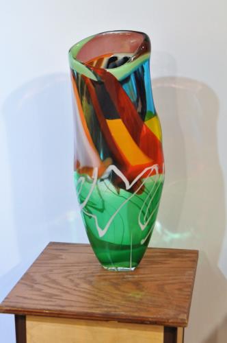 Large vase with multiple colors standing on wooden table