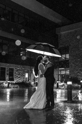 Outside the Marian H Rochelle Gateway Center Laramie Wyoming, wedding kiss umbrella in the rain