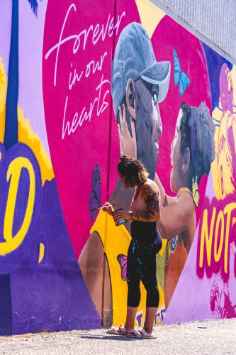 Muralist painting Kobe Bryant mural at Ashe Society dispensary