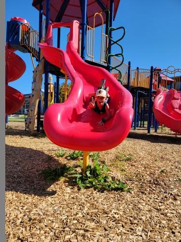 boy slides down red slide on playground