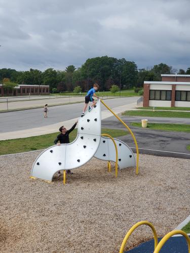 parent helping child climb up rock wall