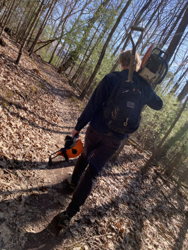 Volunteer Emil Eklund heading to do trail maintenance, carrying a chainsaw