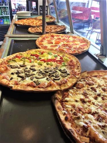 Warming counter with several pizzas lined up on it